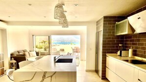 Cocina moderna con una isla grande, salpicadero de azulejos oscuros y vistas a la playa.