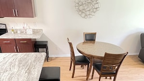 Un comedor con una mesa de mármol, sillas de madera y piso de madera.