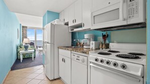Una cocina moderna con armarios blancos, estufa, microondas y cafetera.