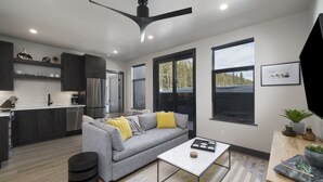 A modern living room with a grey sofa, a coffee table, and a ceiling fan.