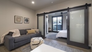 Un salon moderne avec un canapé gris, une table basse blanche et une grande fenêtre.