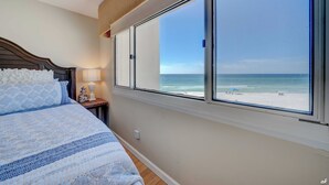 A bedroom with a large window overlooking a beach. - End of Summer Sunset Views PPC3-401 (Panama City Beach)