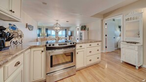 A spacious kitchen with white cabinetry, a stainless steel stove, and a large island. - End of Summer Sunset Views PPC3-401 (Panama City Beach)
