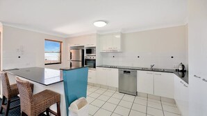 A modern kitchen with white cabinets, stainless steel appliances, and a blue island.