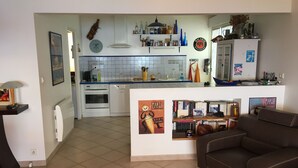 Un espacio habitable compacto con kitchenette, comedor y sala de estar con sofá.