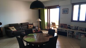 Un comedor con una mesa redonda, sillas y un sofá con cojines.