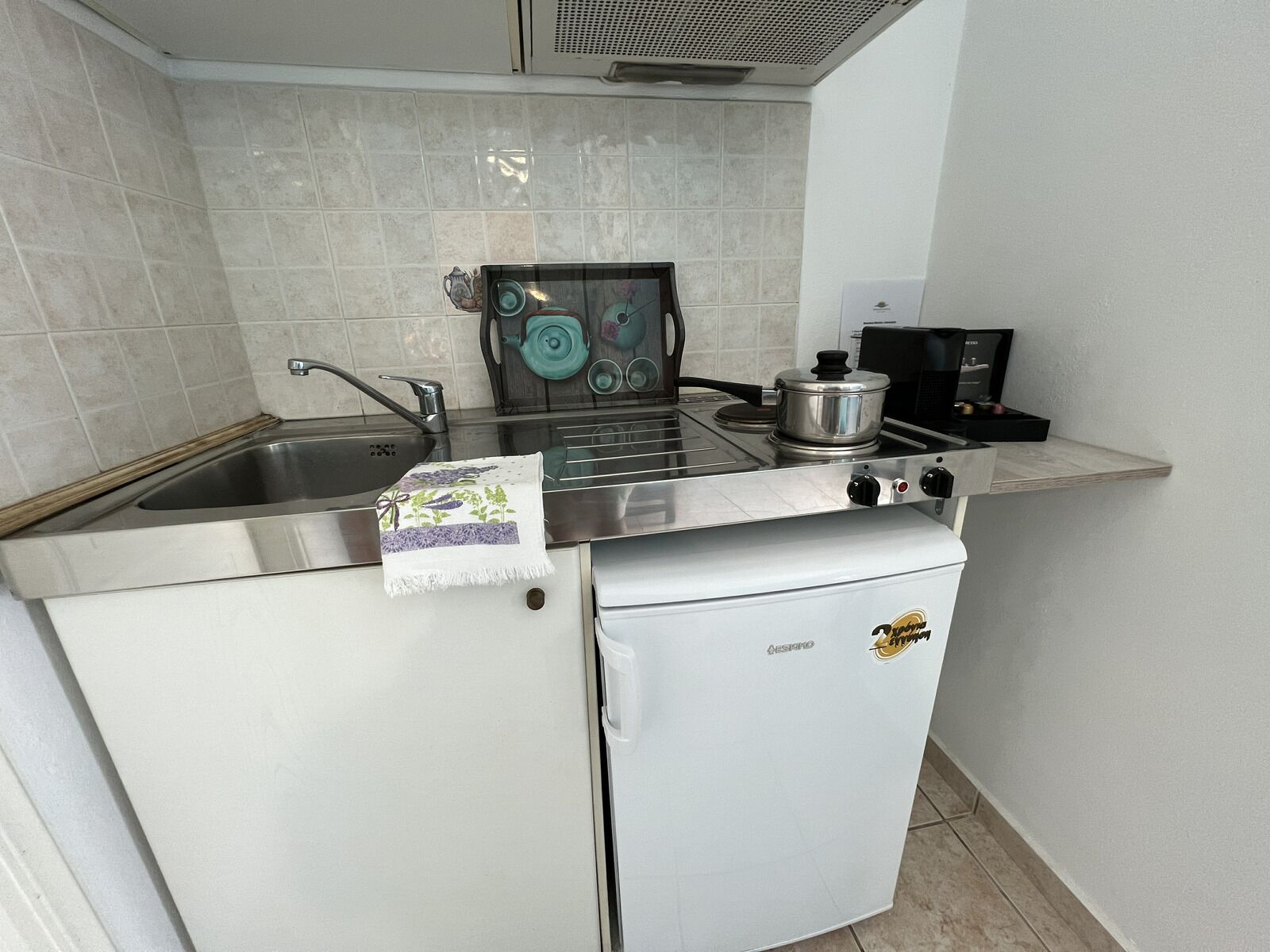 Uma cozinha compacta com pia, fogão e um refrigerador pequeno.