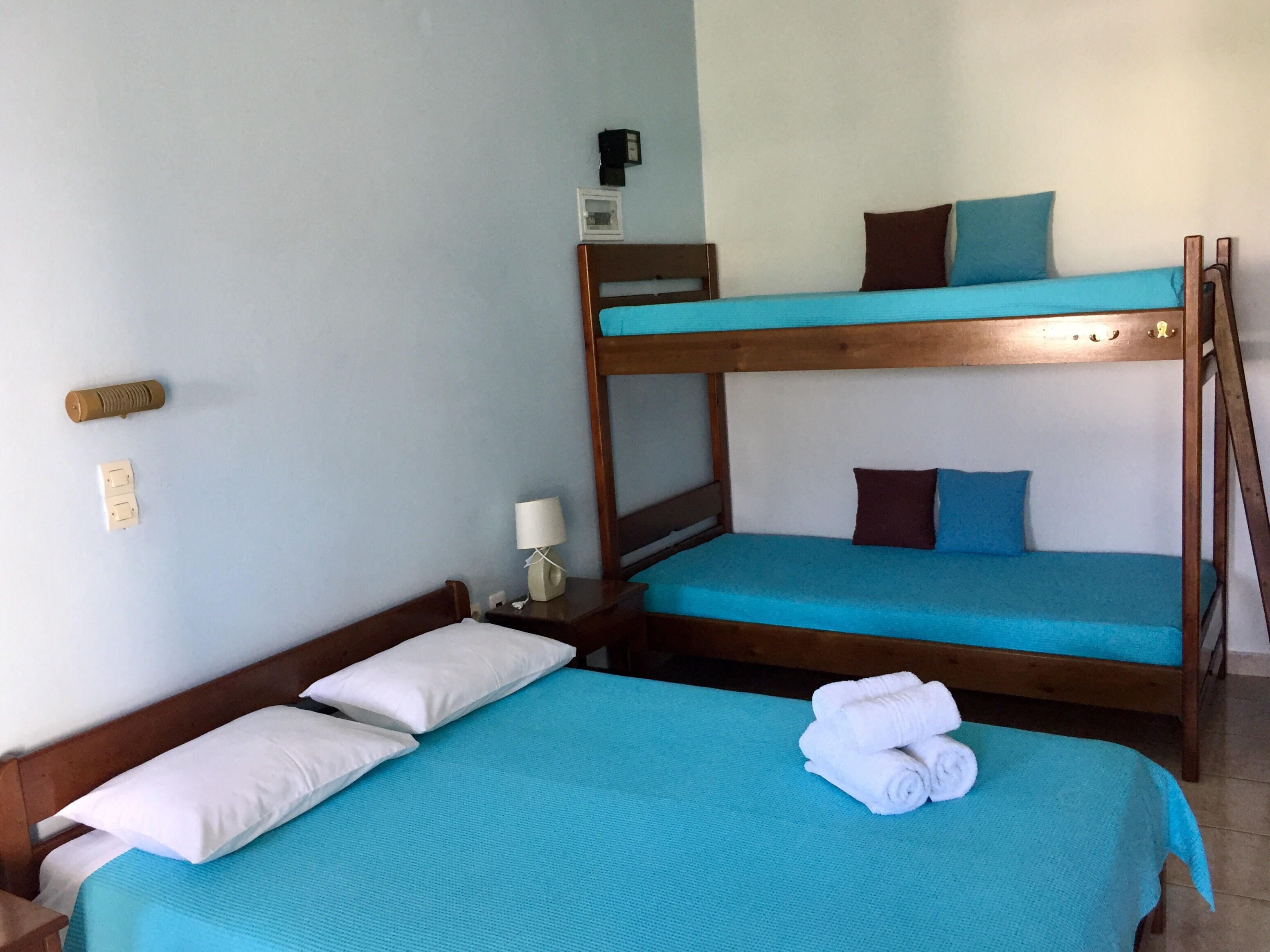 A room with two bunk beds, a bedside table with a lamp, and a wall socket.