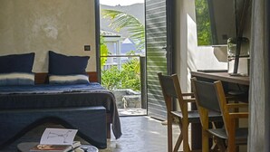 A bedroom with a bed, a desk, and chairs, a small table with a book, and a view of greenery outside. - Luxury villa. Sea view. Private swimming pool. Independent bedroom and suite. (SAINT MARTIN)