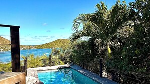 A swimming pool with a wooden deck, two white spherical objects, and a view of the sea. - Luxury villa. Sea view. Private swimming pool. Independent bedroom and suite. (SAINT MARTIN)