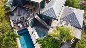 A modern house with a pool, outdoor seating, and a staircase leading to a deck. - Luxury villa. Sea view. Private swimming pool. Independent bedroom and suite. (SAINT MARTIN)