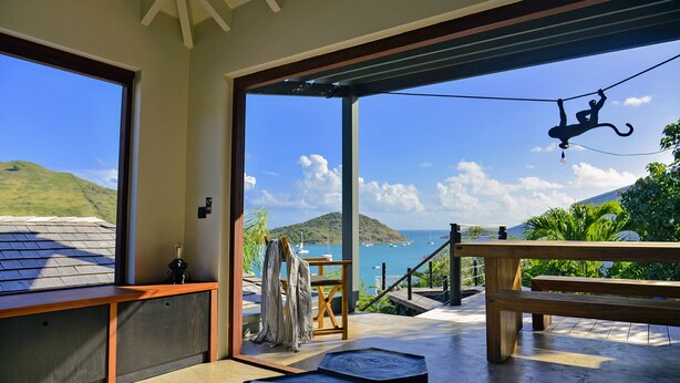 A spacious balcony with a view of the sea, wooden furniture, and a hanging light fixture. - Luxury villa. Sea view. Private swimming pool. Independent bedroom and suite. (SAINT MARTIN)