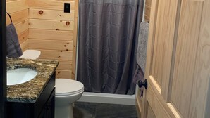 A wooden-paneled bathroom with a shower curtain, a toilet, and a sink with a granite countertop. - Snowmobilers Getaway - ATVers Paradise (Caribou)