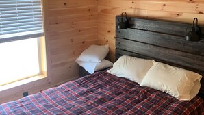 A wooden-paneled room with a bed, a window with blinds, and a ceiling light fixture. - Snowmobilers Getaway - ATVers Paradise (Caribou)