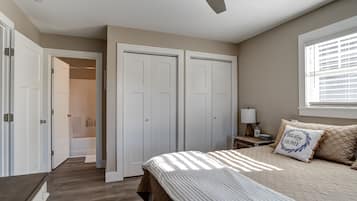 Une chambre à coucher comprenant un lit, une table de chevet, une fenêtre avec des stores et une armoire à deux portes.
