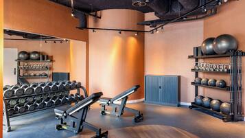 A gym with exercise equipment, including dumbbells, a bench, and medicine balls.