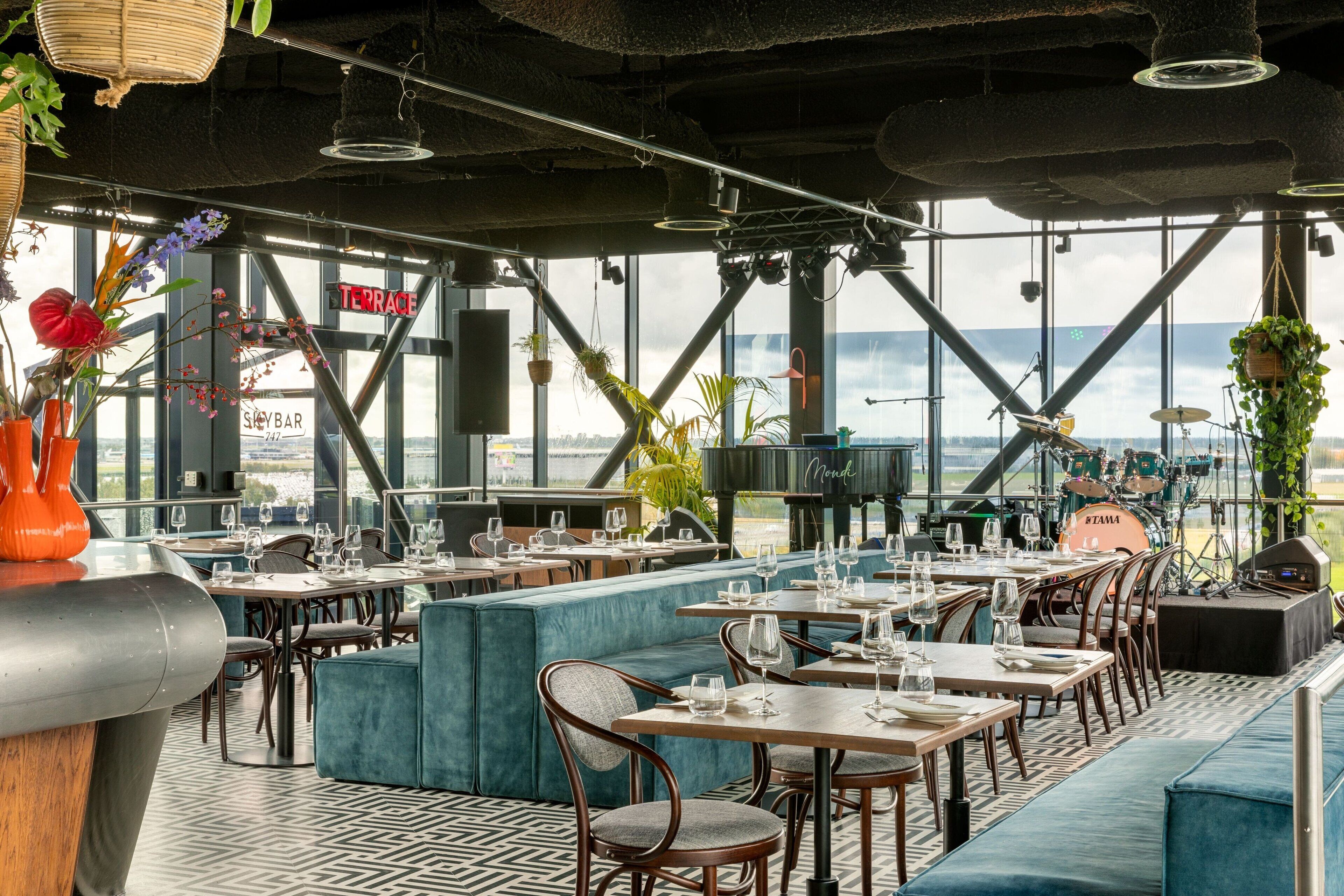 A restaurant with a terrace, tables, chairs, and hanging plants.