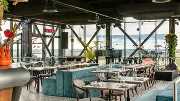 A restaurant with a terrace, tables, chairs, and hanging plants.