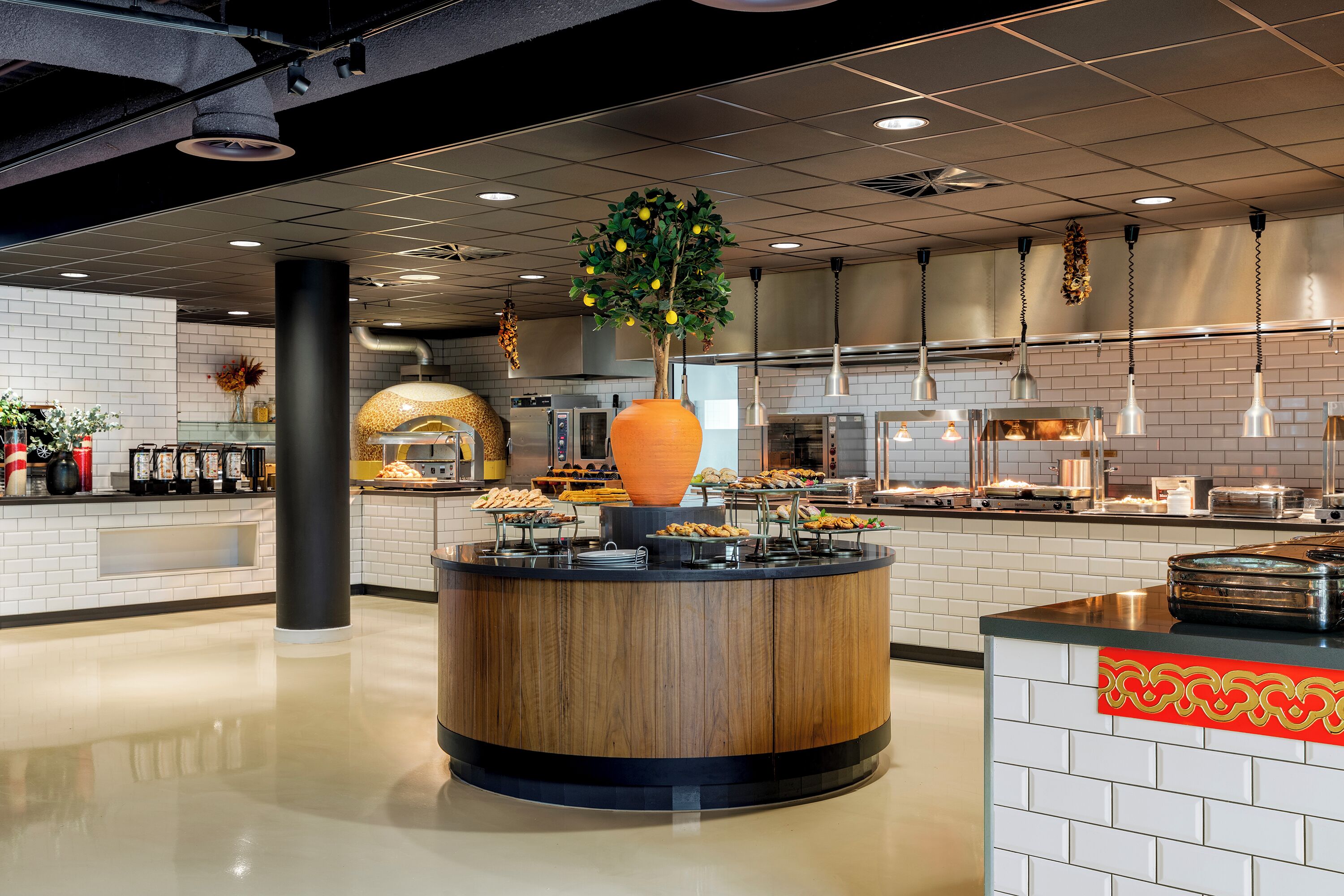 A modern kitchen with a central island, white tiled walls, and a variety of food items displayed.