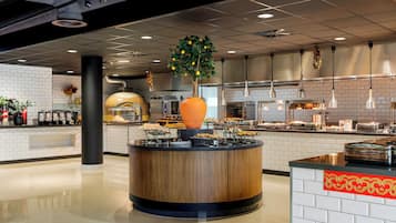 A modern kitchen with a central island, white tiled walls, and a variety of food items displayed.