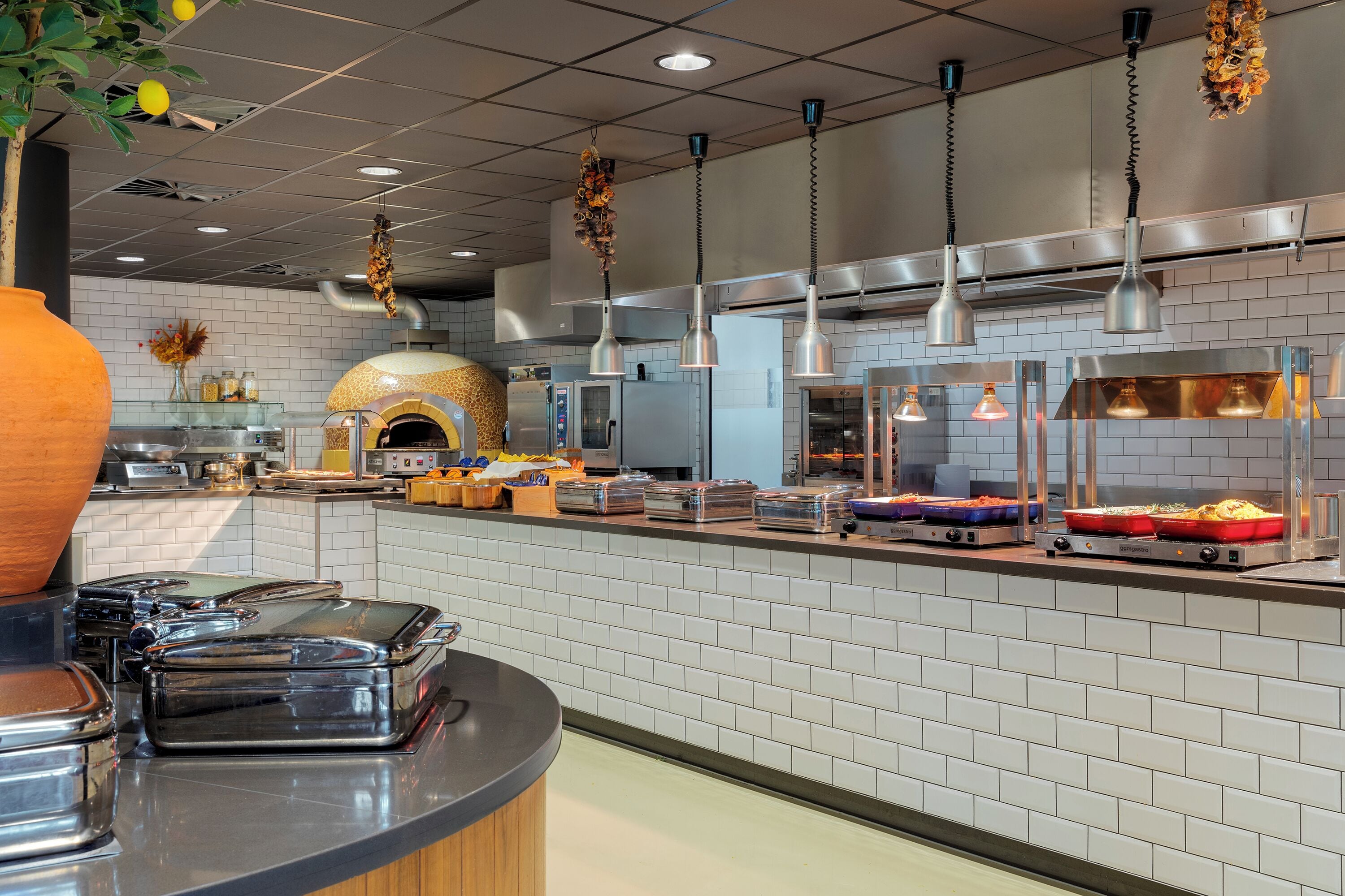Una cocina moderna con protector mural de ladrillo, electrodomésticos de acero inoxidable y varios dispensadores de alimentos.