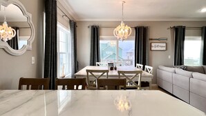 A dining area with a marble table, white chairs, and two chandeliers. - Walk to tradin post!North cape, private pool, awesome patio & steps to beach! (Port Saint Joe)