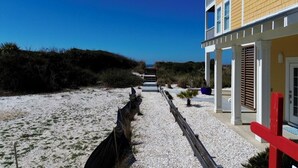 A pathway leading to a building with a balcony and a door. - Walk to tradin post!North cape, private pool, awesome patio & steps to beach! (Port Saint Joe)