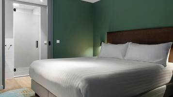 A neatly made bed in a room with green walls and a wooden headboard.