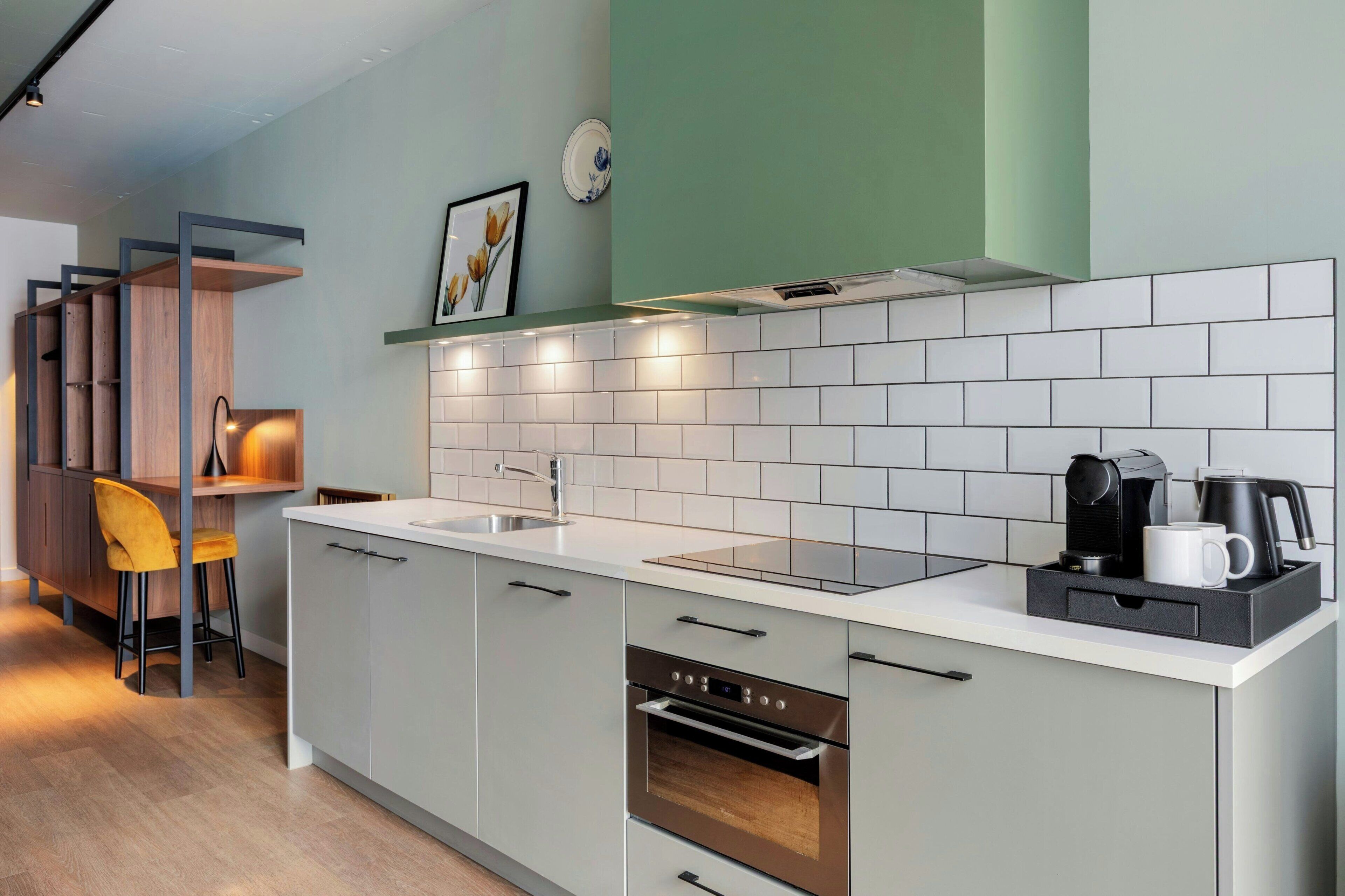 A modern kitchen with a white countertop, stainless steel appliances, and a green accent wall.