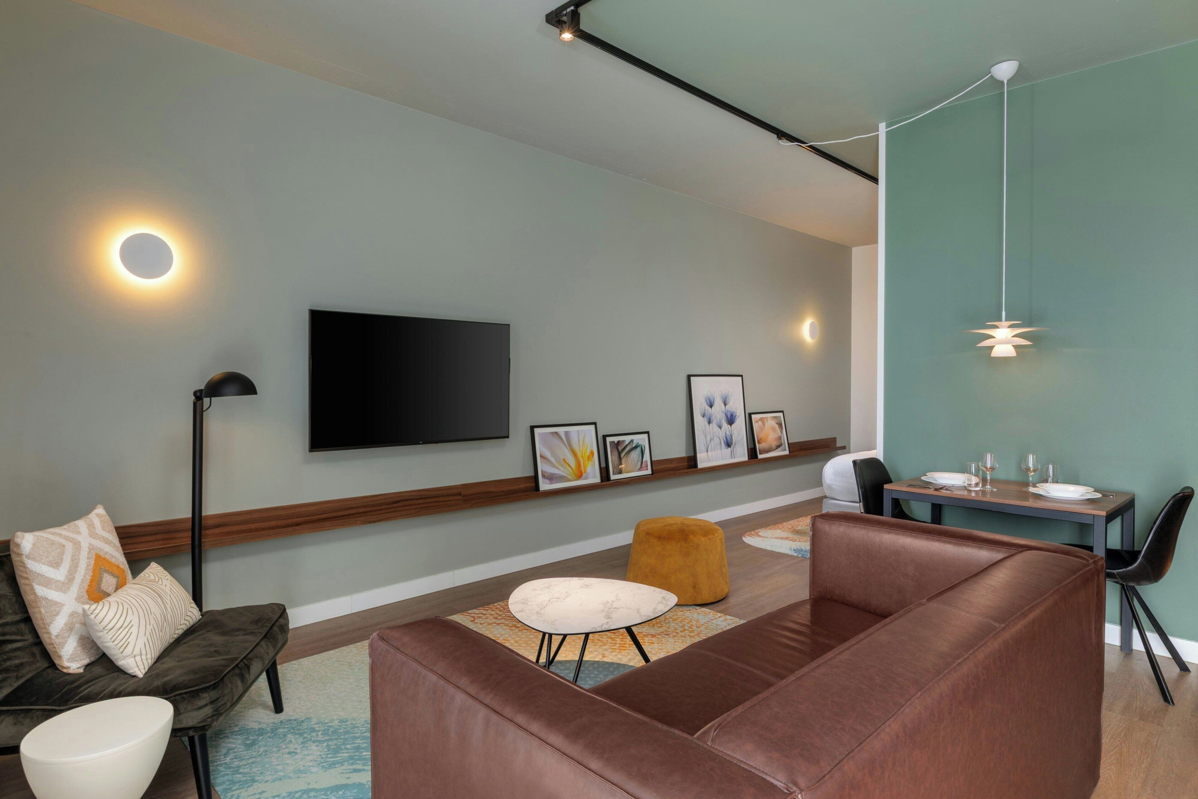 Una sala de estar moderna con un sofá, un reposapiés y una mesa de comedor.