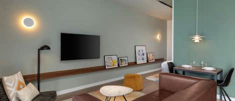 A modern living room with a sofa, ottoman, and dining table.