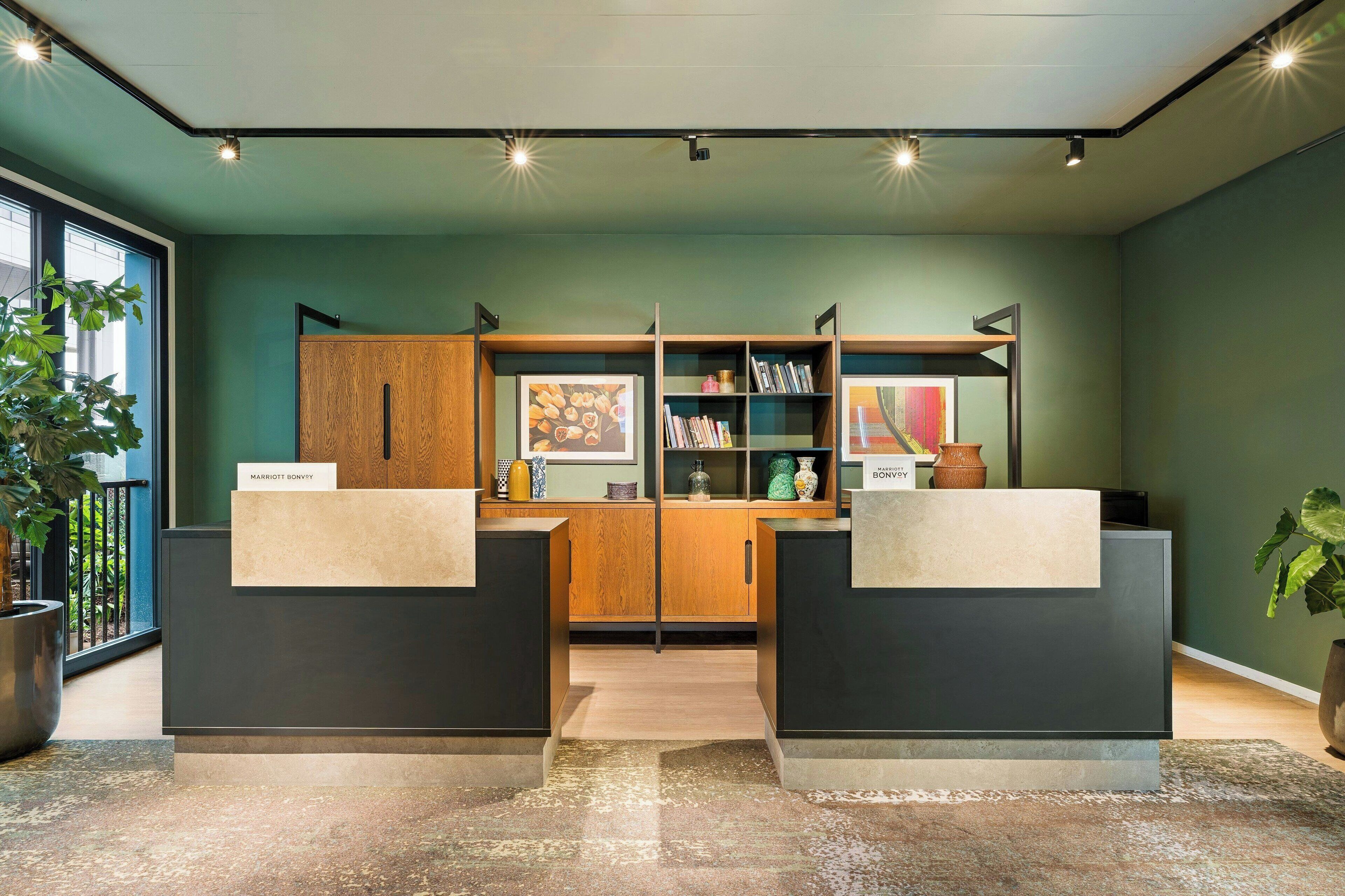 A reception area with a modern design, featuring a reception desk, a wooden cabinet, and a bookshelf with various items.