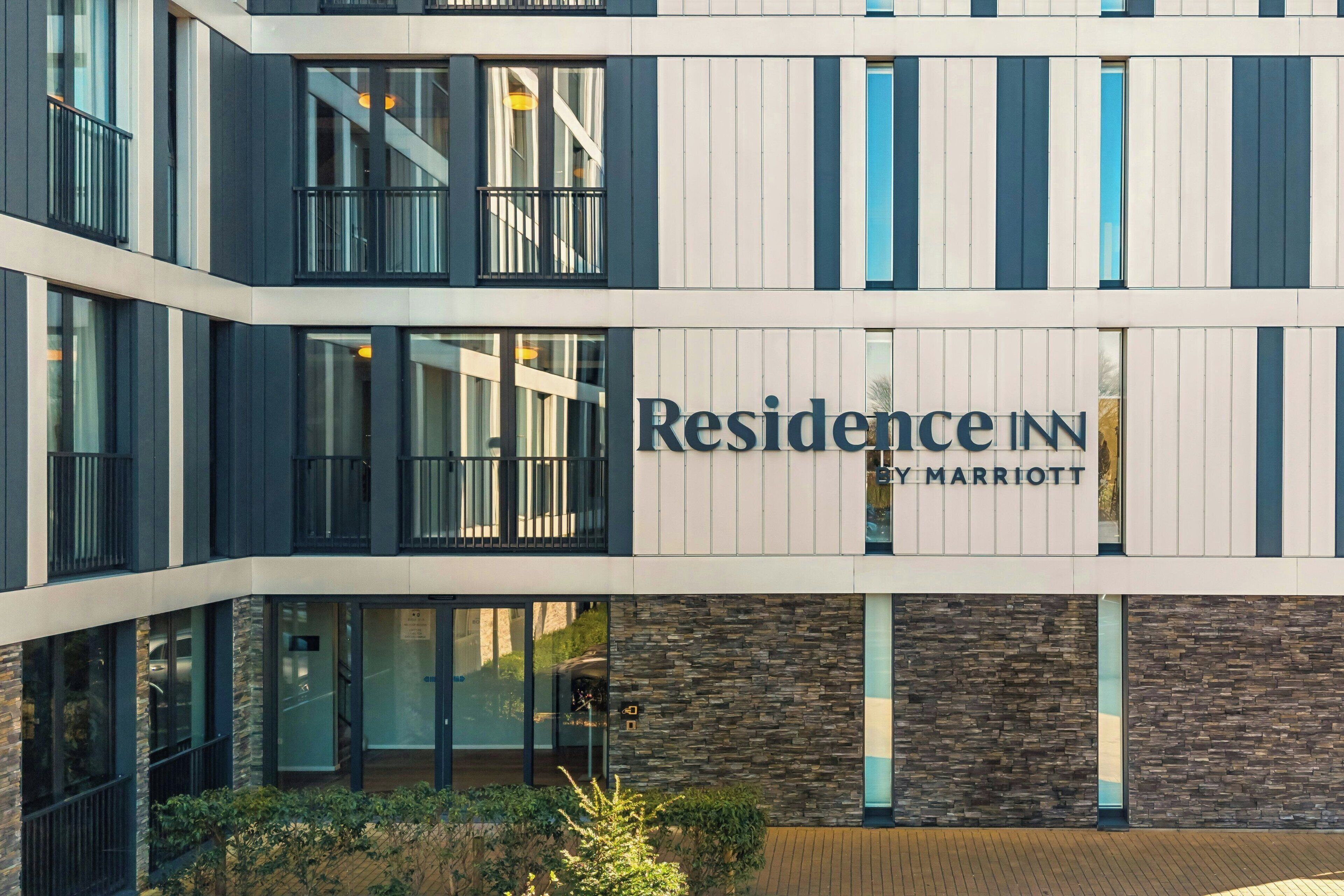 A multi-story hotel with a modern facade, large windows, and a sign reading 'Residence IN by Marriott.'