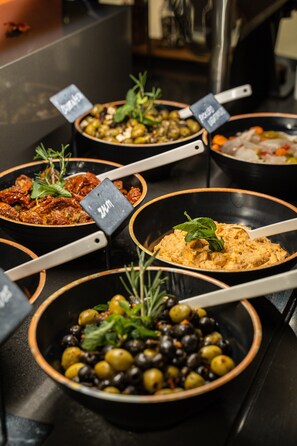 A buffet with various dishes in black bowls with orange rims, each labeled with a name tag. - Residence Inn by Marriott Amsterdam Schiphol Airport (Badhoevedorp)