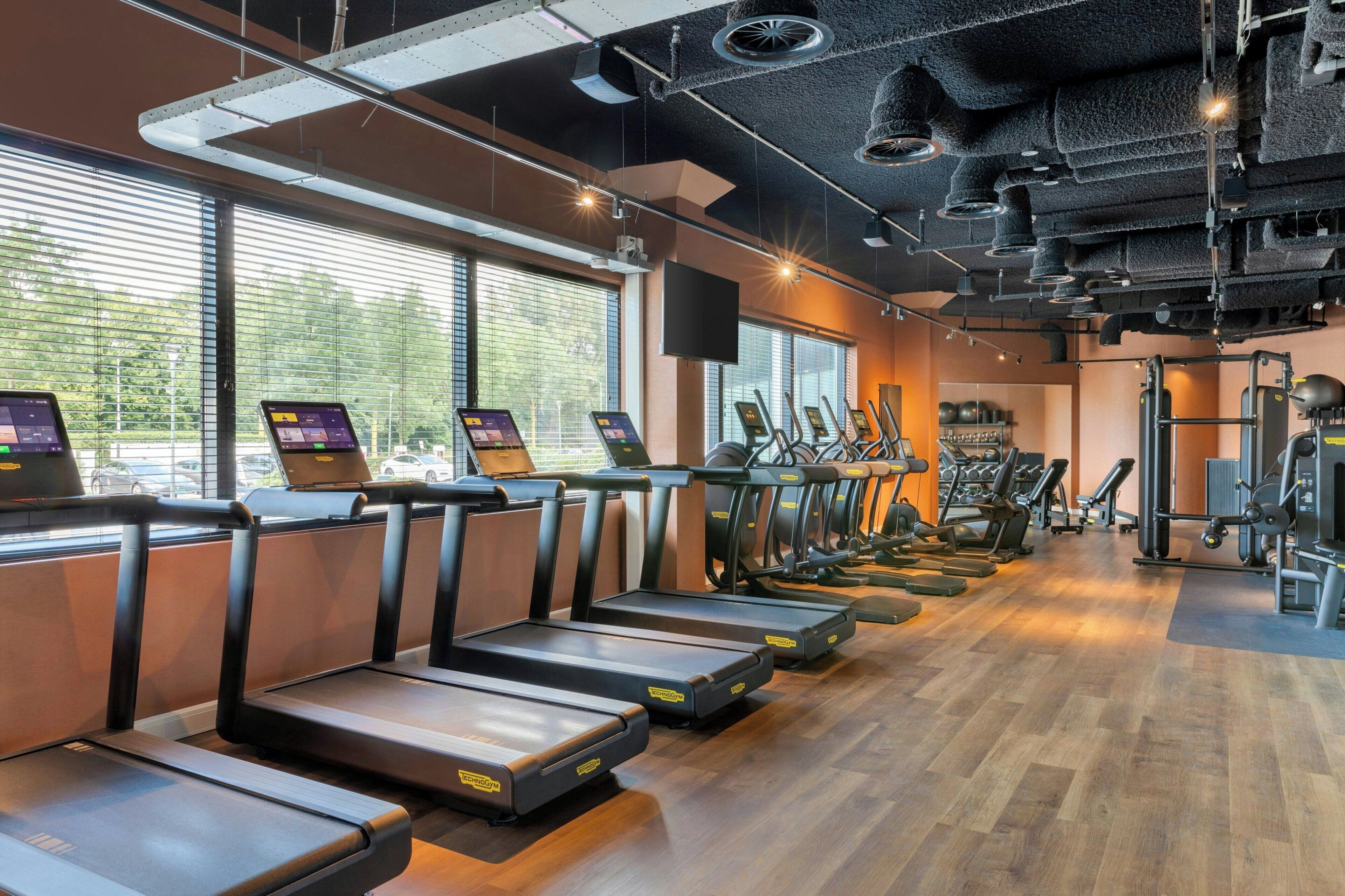 A gym with treadmills, elliptical machines, and weight equipment.