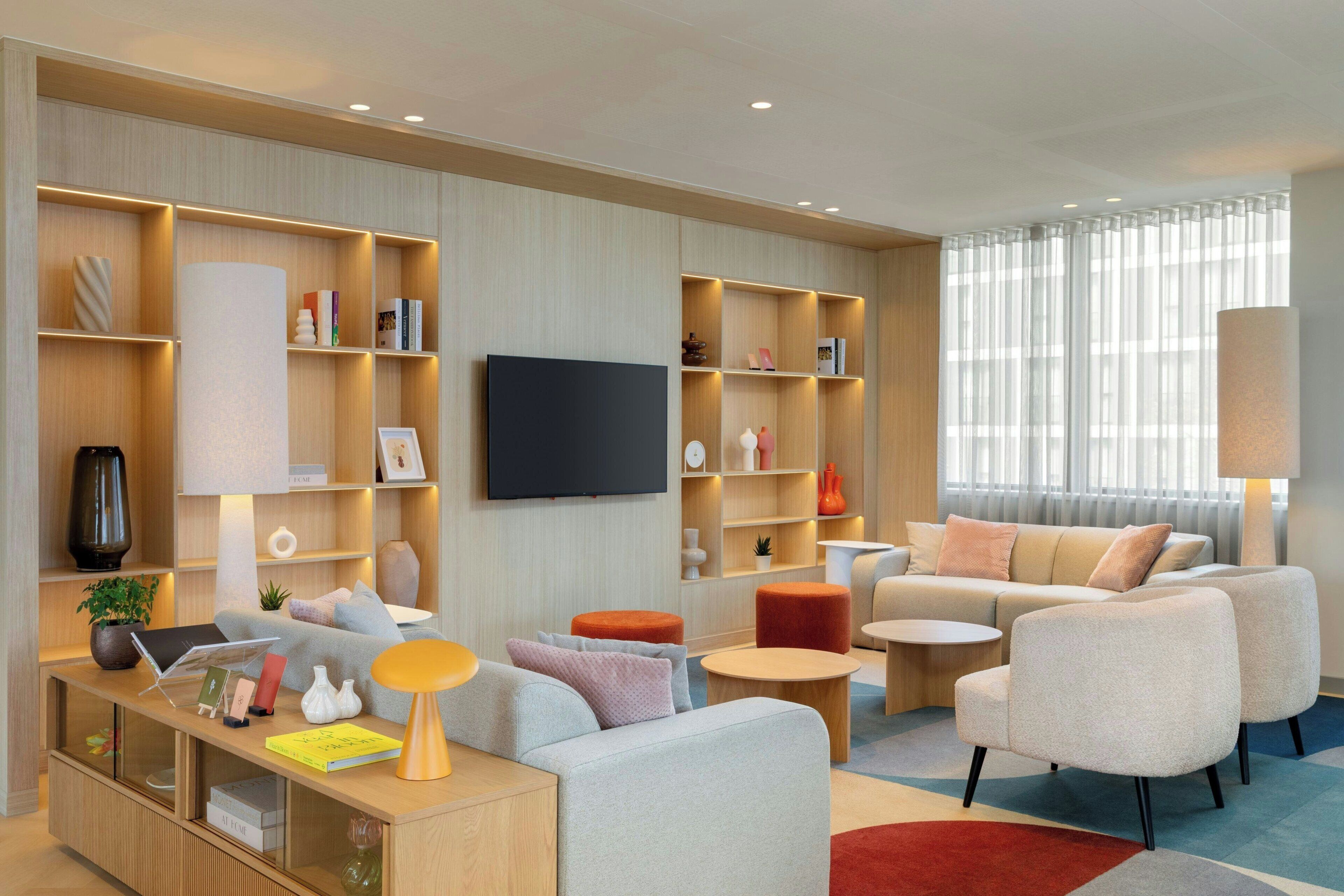 Una sala de estar moderna con un sofá, sillones, una mesa de centro y un televisor montado en la pared.