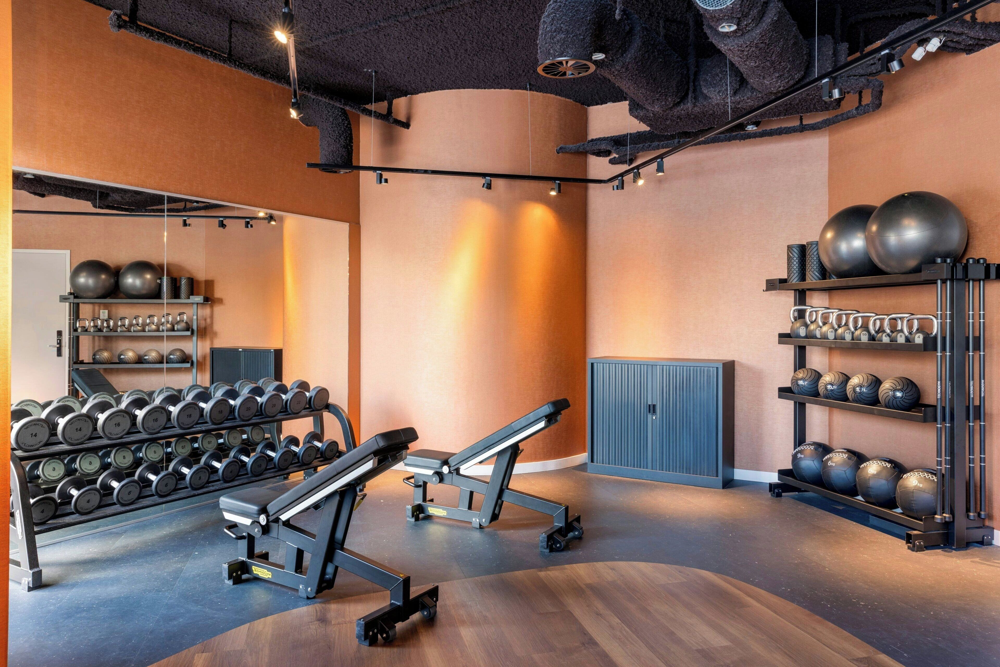 Una palestra con attrezzature per esercizi, una panca e uno specchio a parete.