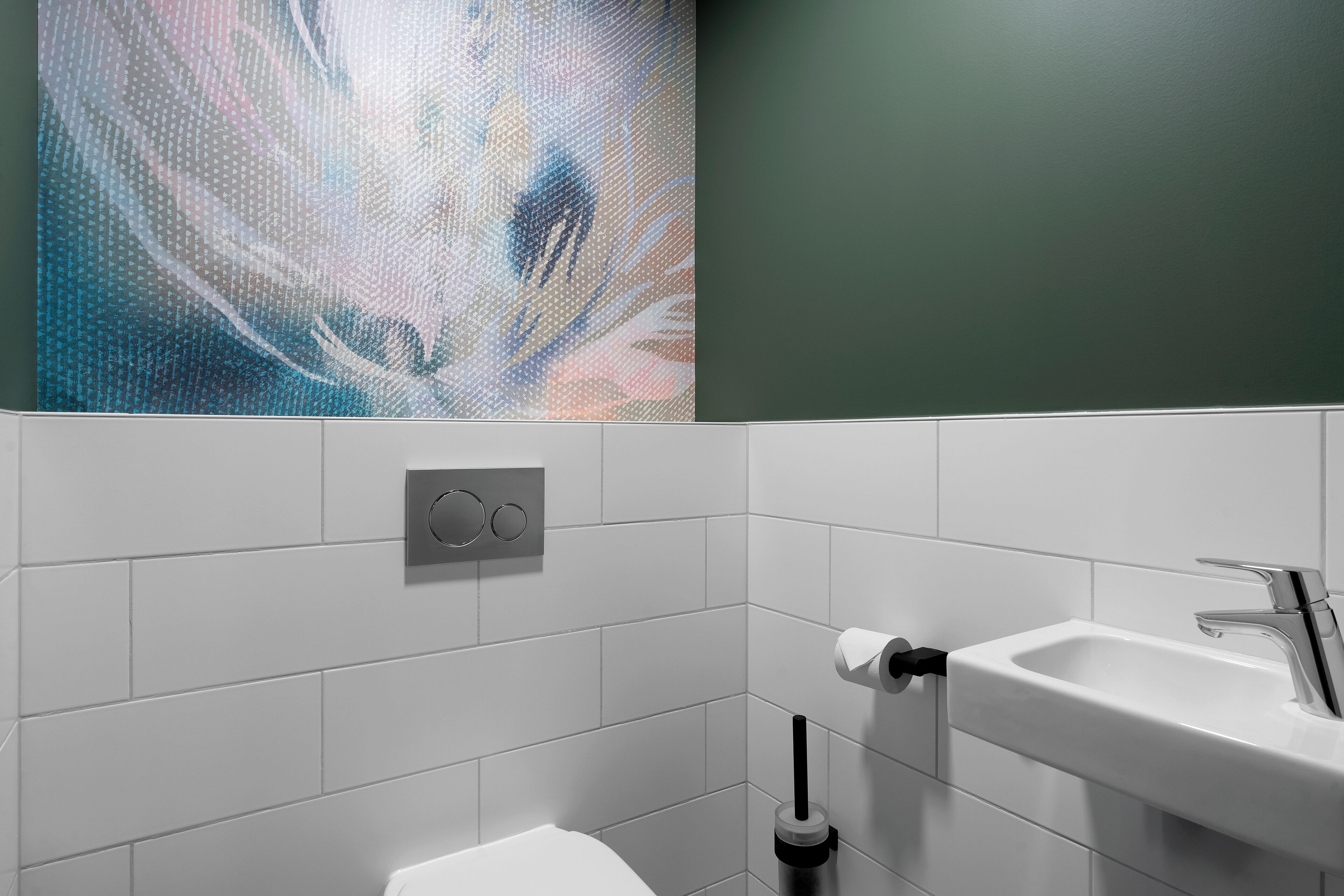 Un baño moderno con azulejos blancos, un lavamanos blanco, un inodoro y un ambientador fijado a la pared.