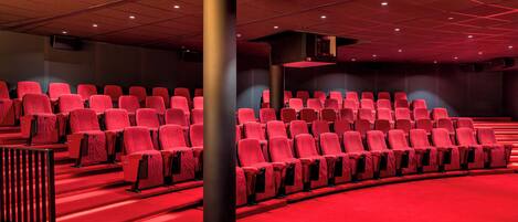 A theater with rows of red seats and a red carpeted floor.