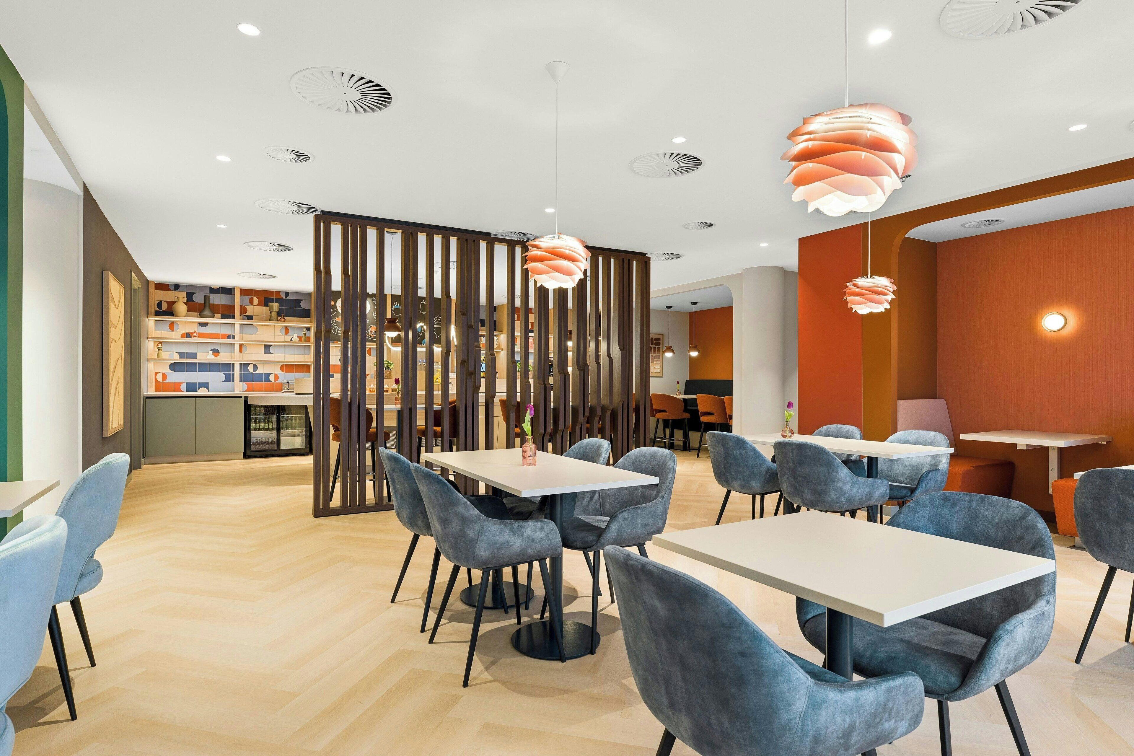 A modern dining area with tables, chairs, and pendant lights.