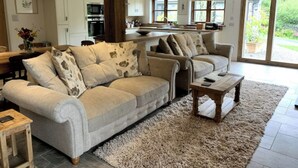 A spacious living room with a large beige sofa, a wooden coffee table, and a fluffy rug. - Barn and Stables in tranquil gardens and farmland (Boscastle)
