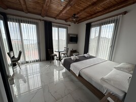 Habitación de hotel con cama, escritorio, silla y televisor.