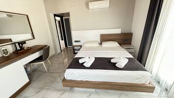 A modern hotel room with a bed, a desk, a chair, and a large mirror.