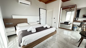 A modern hotel room with a large bed, wooden headboard, white walls, and a marble floor.