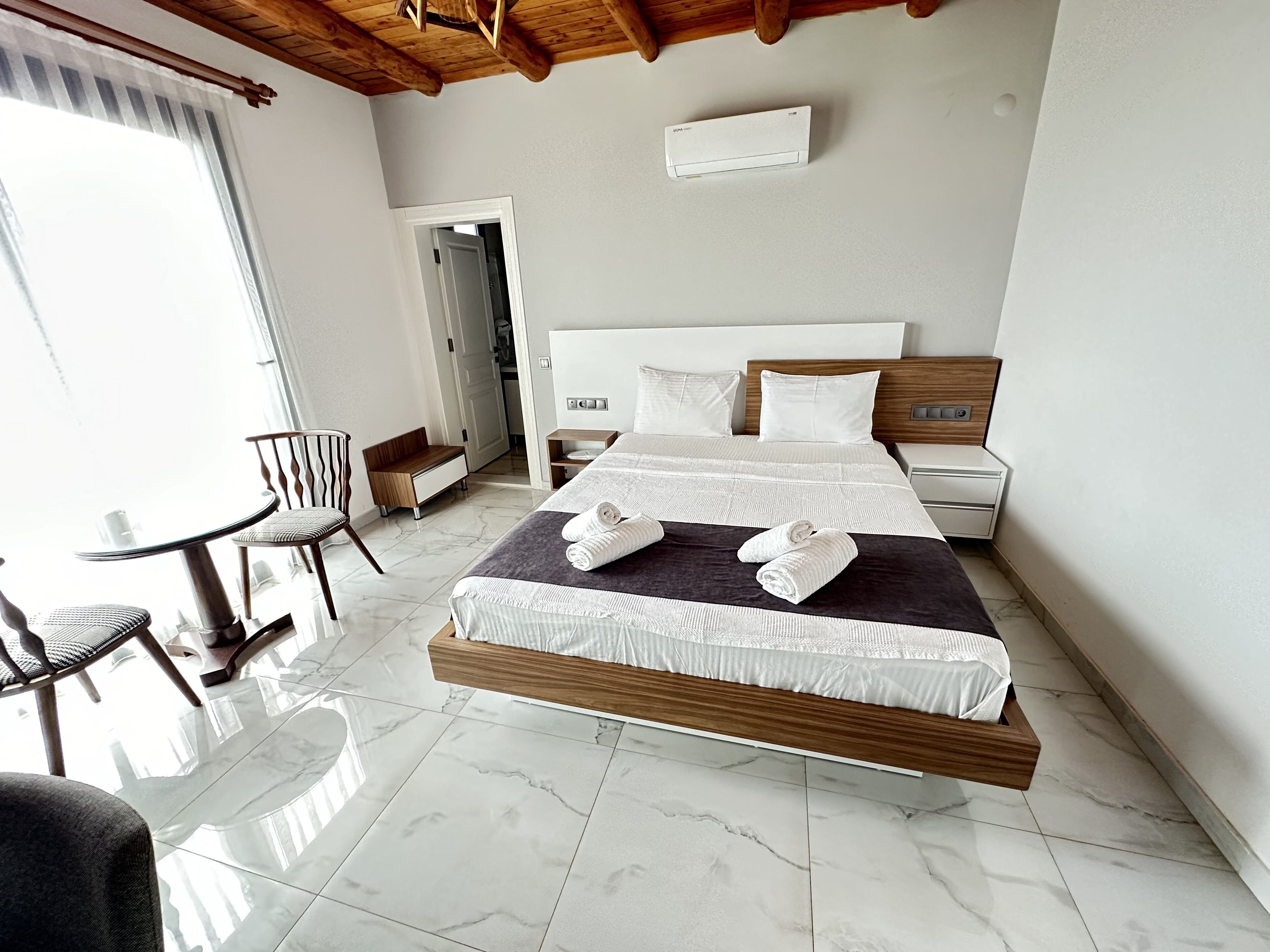 Una moderna camera d'albergo con un grande letto, un comodino, una sedia e un tavolino.