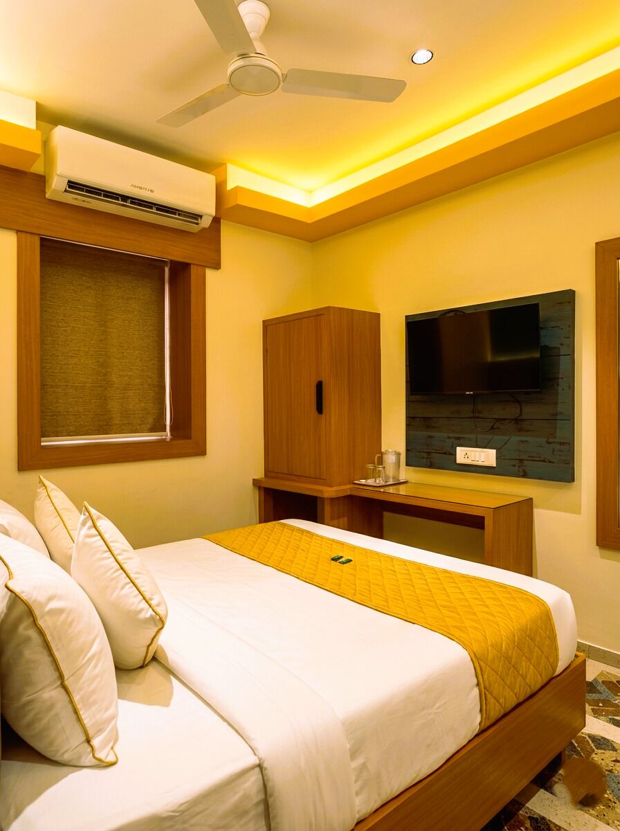 Una habitación de hotel con cama, escritorio, televisor y aire acondicionado.