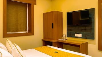 A hotel room with a bed, a desk, a television, and an air conditioning unit.