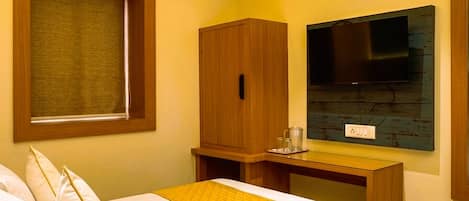 Una habitación de hotel con cama, escritorio, televisor y aire acondicionado.