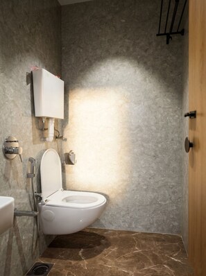 Un baño moderno con inodoro, lavamanos empotrado en la pared y zona de ducha.