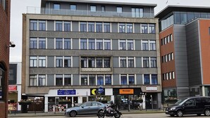 A multi-story building with a modern architectural design, featuring a mix of brick and glass facades.